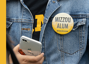 Close up of jean jacket with Mizzou shirt and button
