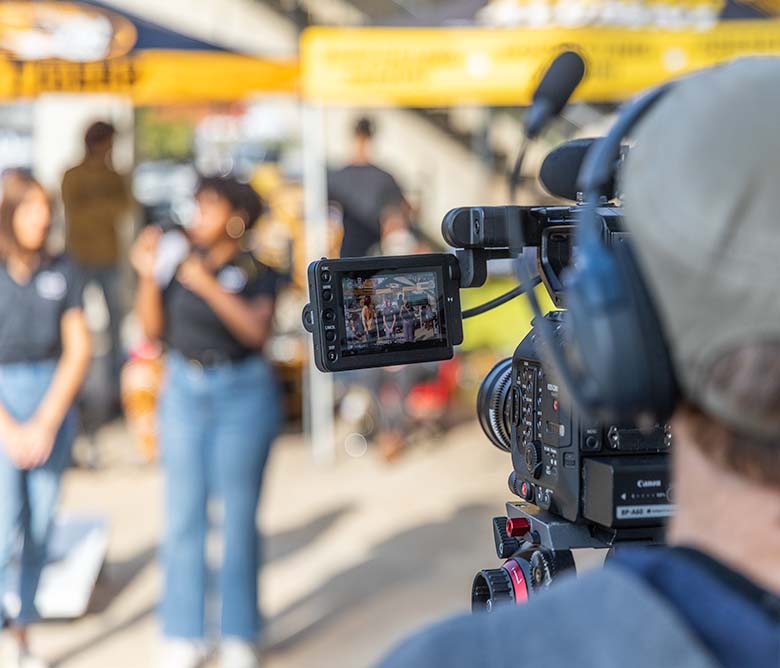 Mizzou Visual Productions videographer looking into the viewfinder on a camera.